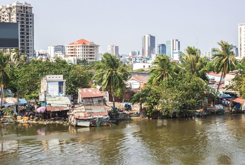 Poor houses along the river in Ho Chi Minh City, Vietnam with skyscrapers in the distance