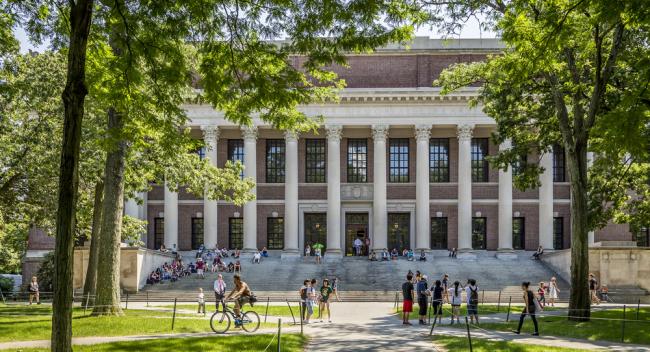 people walk and bike through Harvard Yard with Widener Library in the background