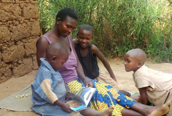 A Rwandan mother reads to her three young children as part of the Sugira Muryango implementation program.