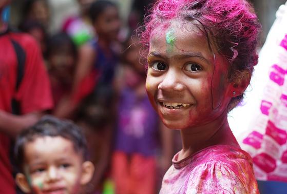 A young girl covered in pink paint celebrates in Mumbai, India.