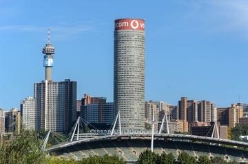 Johannesburg cityscape featuring prominent landmarks including the cylindrical Telkom Tower and the adjacent Hillbrow Tower against a clear blue sky