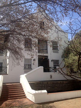 A white multi-story building with a gabled roof and a central stair entrance