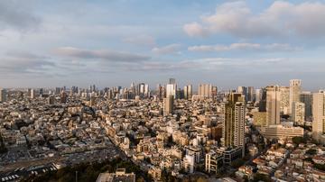 Aerial view of Tel Aviv cityscape with low-rise and high-rise buildings under a partly cloudy sky