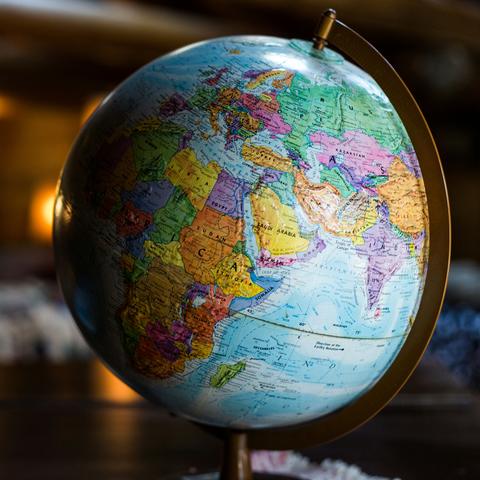 A colorful globe showing continents including Africa, Europe, and Asia, sitting on a wooden table indoors