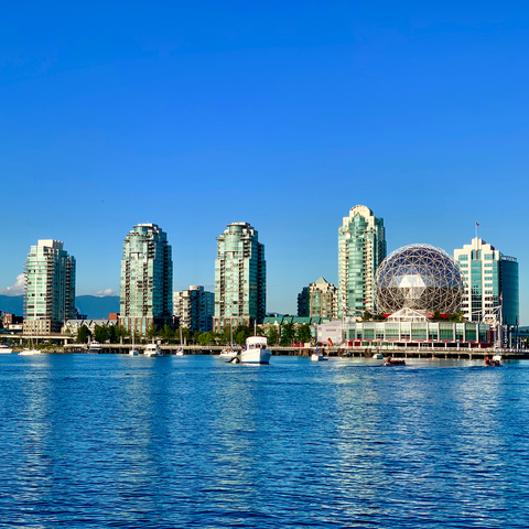 A waterfront city skyline featuring modern high-rise buildings and a distinctive geodesic dome structure