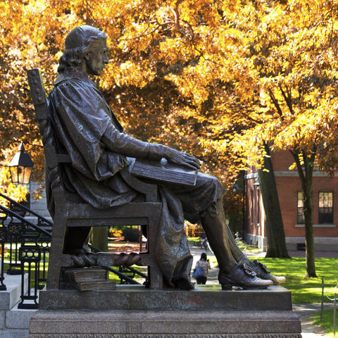 Bronze statue of a man sitting in a chair with a book on his lap