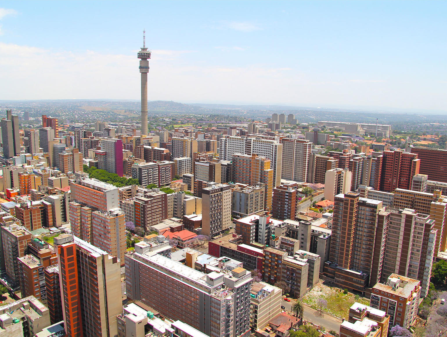 Aerial view of Johannesburg cityscape with high-rise buildings and a telecom tower rising above the skyline