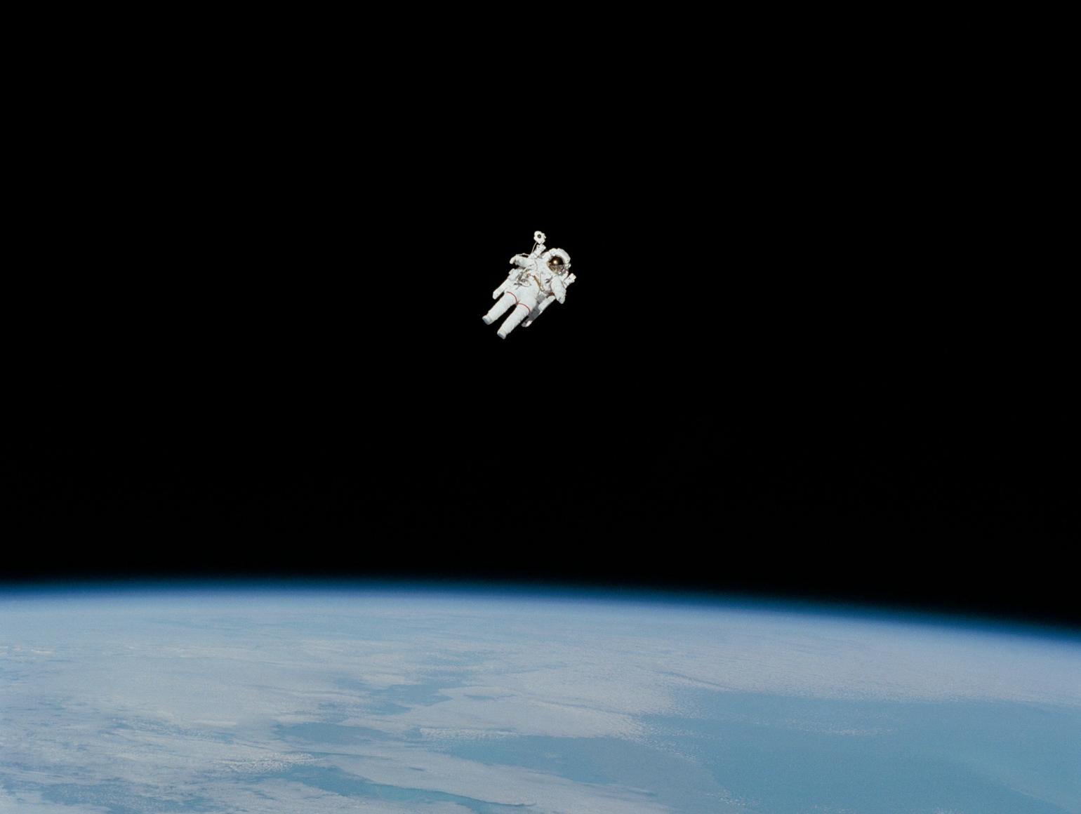 Astronaut in a white spacesuit floating in space above Earth
