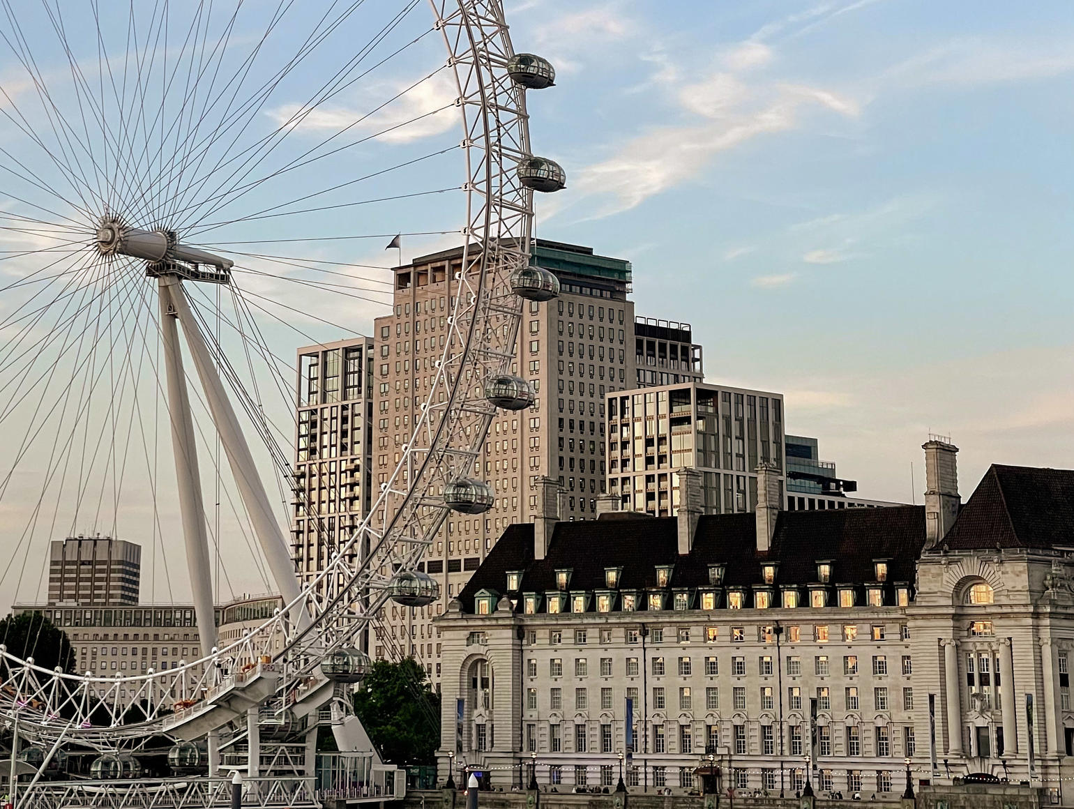 London Eye, a large ferris wheel on the South Bank of the River Thames, with surrounding buildings under a clear blue sky